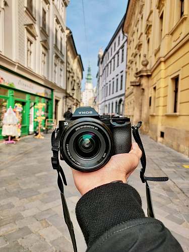 person man holding Sony DSLR camera in the street camera