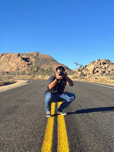 person man sitting in road taking picture asphalt