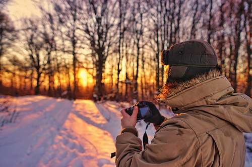 person man wearing brown jacket holding black camera photographer