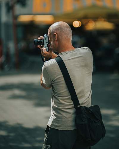 person man wearing gray crew-neck T-shirt holding DSLR camera photographer