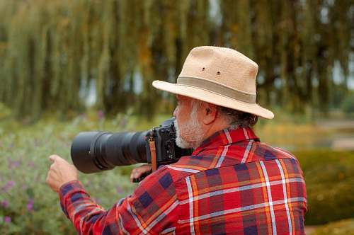 person man wearing red dress shirt holding DSLR camera apparel