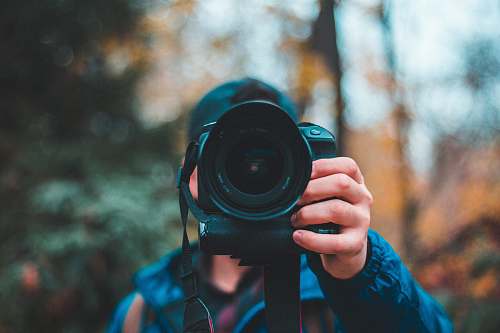 photographer selective focus photography of man holding black DSLR camera camera