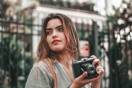 person selective focus photography of woman wearing gray top holding camera camera