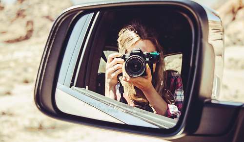person woman holding DSLR camera facing side mirror mirror