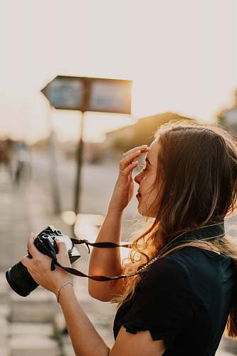 person woman in black shirt holding DSLR camera photographer