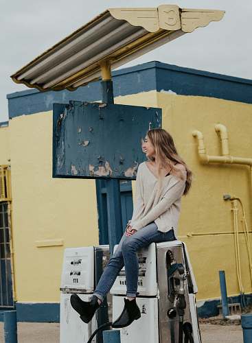 person woman sitting on white gasoline pump machine during daytime people