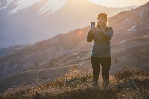 person woman standing on the grass field using smartphone standing