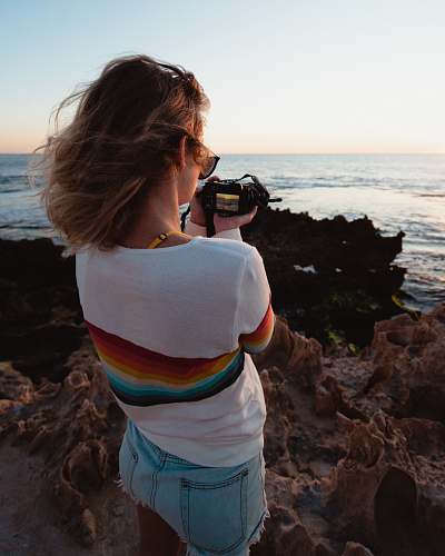 person woman taking photo of seashore during daytime photographer
