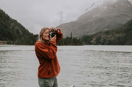 person woman taking photo using camera mountain