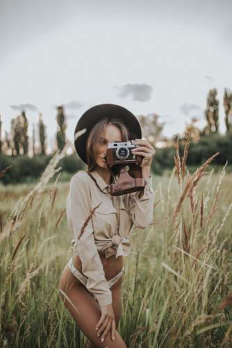 person woman wearing white pantie holding gray and brown camera plant
