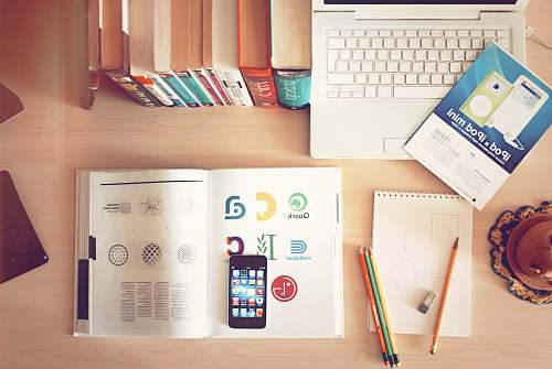 desk pencils and smartphone on top of books apple