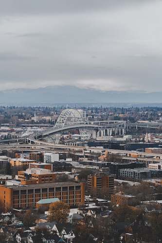 landscape aerial photography of city with high-rise buildings viewing mountain under gray sky outdoors