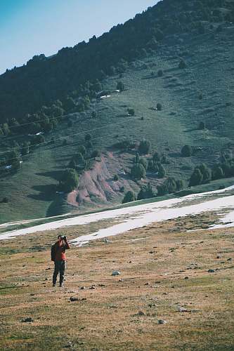 kyrgyzstan man wearing orange shirt hiking landscape