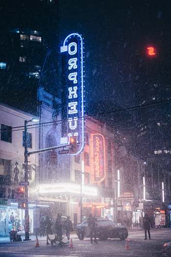outdoors people walking near lighted buildings at nighttime snow