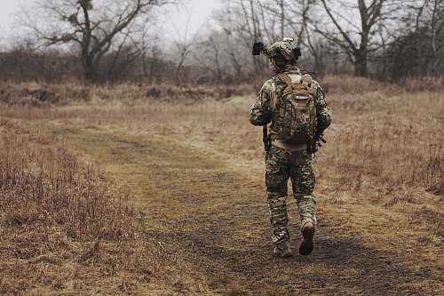human man walking on brown grass field military