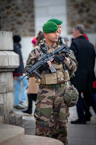 human soldier with rifle stands guard in front of building gun