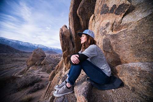 clothing woman sitting on brown rock formation footwear