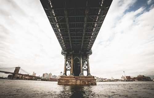 building grey steel bridge over sea under grey and blue sky under bridge