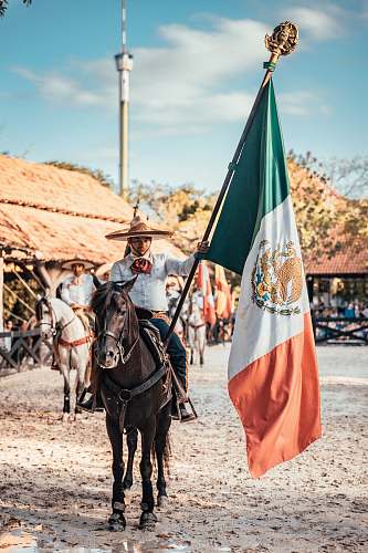 symbol man riding on horse while holding flag of Mexico horse
