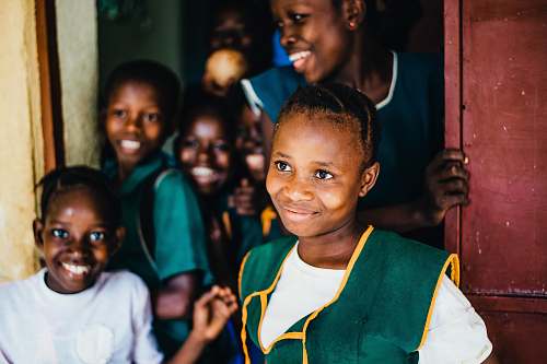 person children smiling while standing near open door happy school