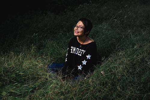 person woman sitting on grass smiling and looking up during nighttime people
