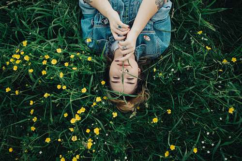 human woman lying on grass ground with yellow petaled flowers person