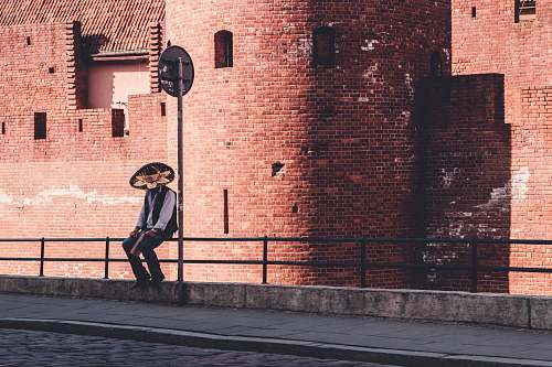 human man sitting on metal rails brick