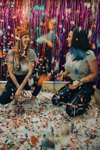 confetti two women kneeling under falling confetti paper