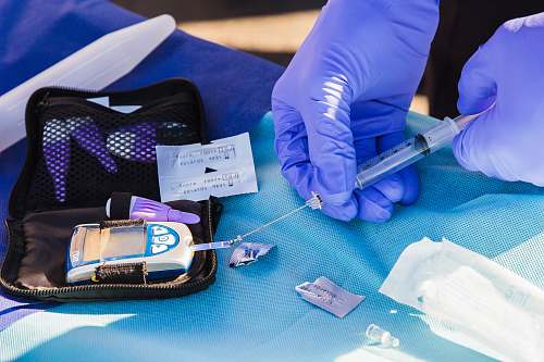 clothing person using disposable syringe put specimen on blue and white glucose meter person