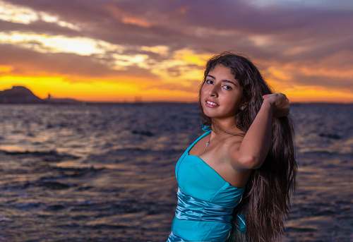 clothing selective focus photography of smiling woman standing near sea evening dress