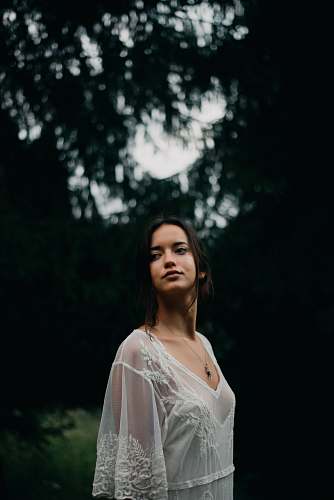 clothing selective focus photography of woman standing near trees wearing white sheer top robe