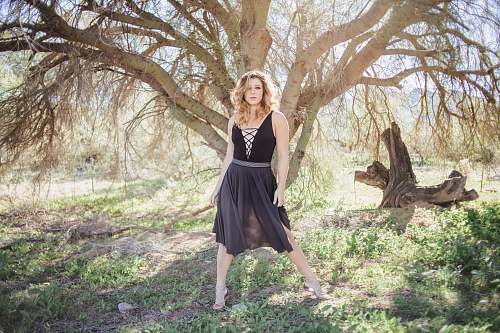 clothing woman in black dress standing in front of tree evening dress