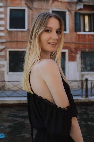 clothing woman in black off shoulder dress standing near canal evening dress