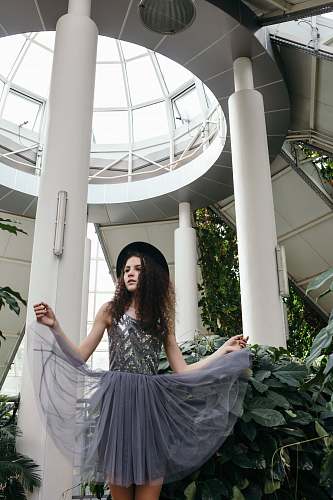 clothing woman in gray sleeveless dress wearing black hat under white dome fashion