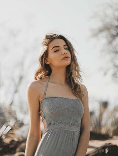 clothing woman in gray spaghetti strap dress standing outside during daytime gown