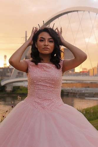 clothing woman wearing pink sleeveless dress standing and touching her crown evening dress