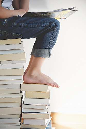 reading person sitting on stack of books while reading read