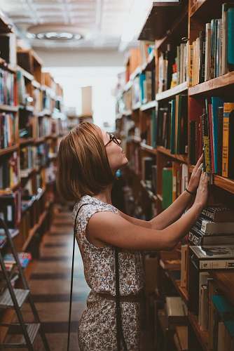library woman standing between library book shelves woman