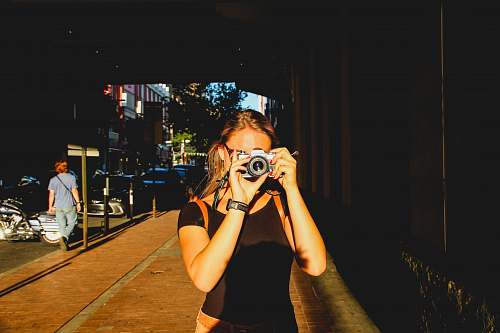 human selective focus photography of woman holding gray camera person