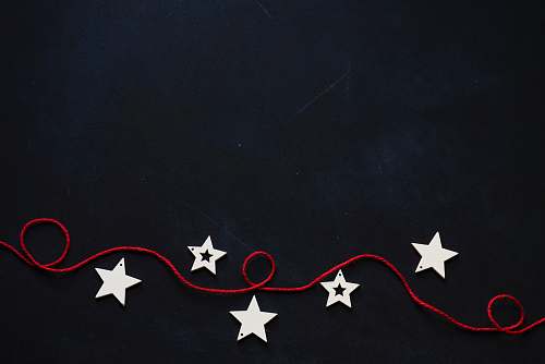 holiday white stars cutout on black surface with red string blackboard