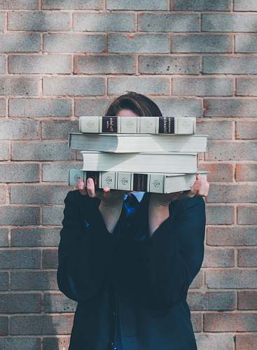 apparel person holding pile of books near face grey