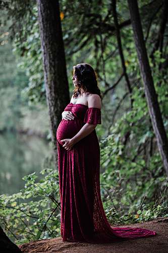 apparel pregnant woman standing near trees during day gown