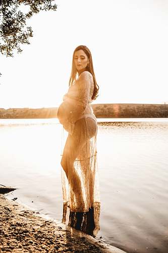 apparel pregnant woman standing on body of water fashion