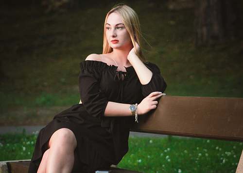 apparel woman in black off-shoulder dress sitting on wooden bench evening dress