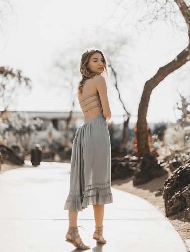 apparel woman in gray spaghetti strap dress standing on road during daytime gown