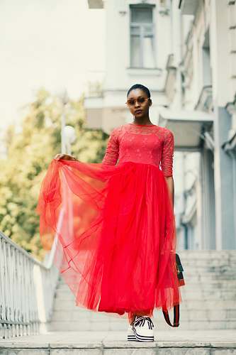 apparel woman in red elbow-sleeved dress standing beside white metal rail gown