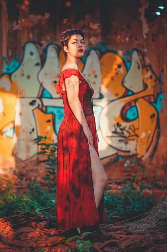 apparel woman in red slit dress standing near graffiti wall evening dress