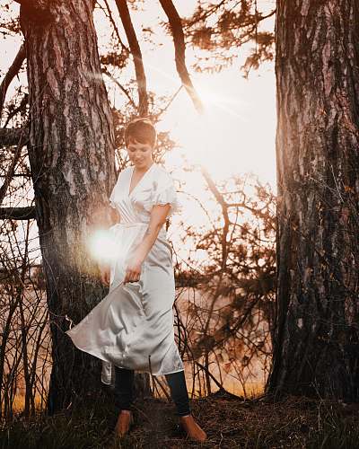 apparel woman standing beside tree fashion