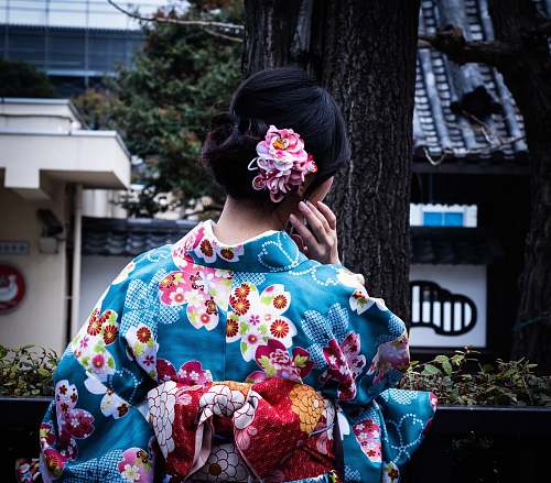 fashion woman wearing blue and multicolored floral kimuno standing and facing near tree apparel