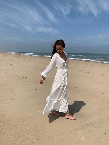apparel woman wearing long-sleeved dress walking on seashore fashion